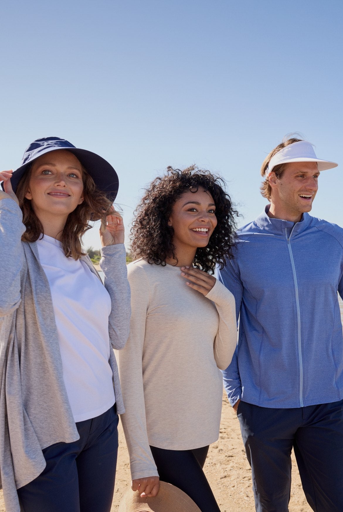 Three people walking outdoors on a sunny day, wearing casual clothing.
