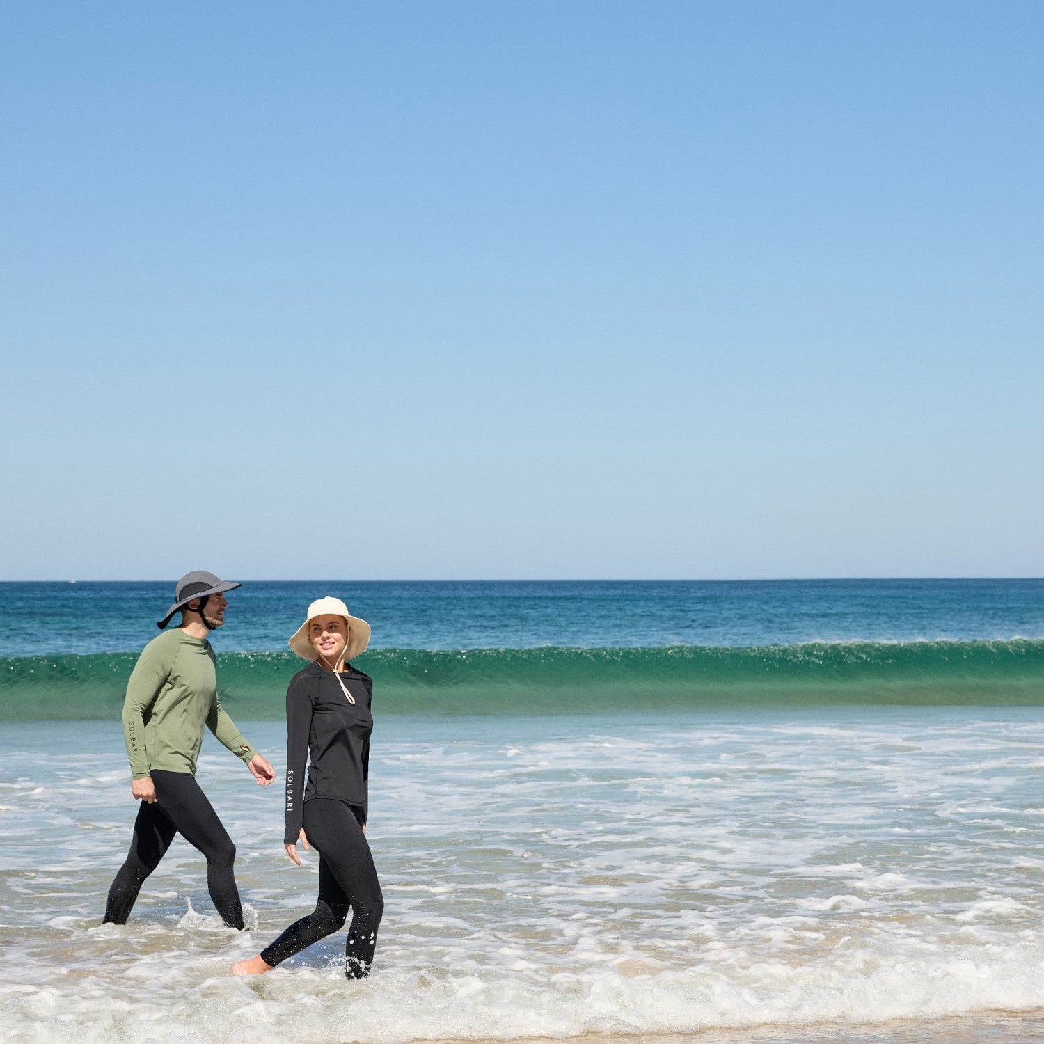 Man and woman walking in the sea wearing Solbari UPF 50 hats